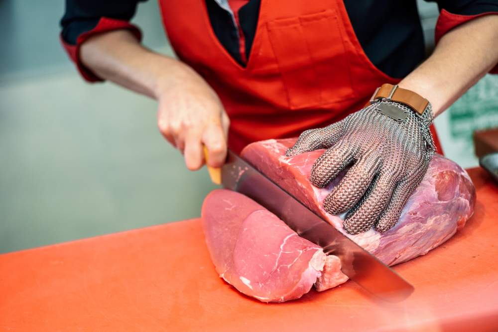 woman-cutting-fresh-meat-butcher-shop-with-metal-safety-mesh-glove