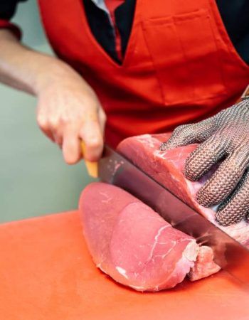woman-cutting-fresh-meat-butcher-shop-with-metal-safety-mesh-glove