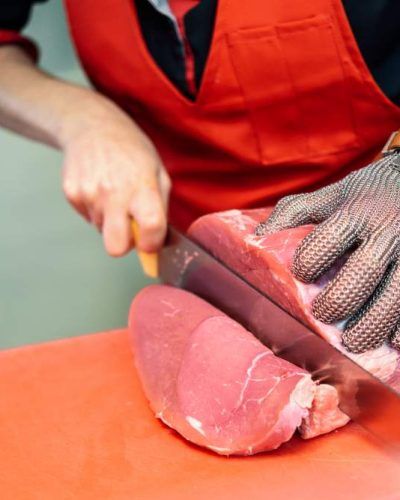 woman-cutting-fresh-meat-butcher-shop-with-metal-safety-mesh-glove